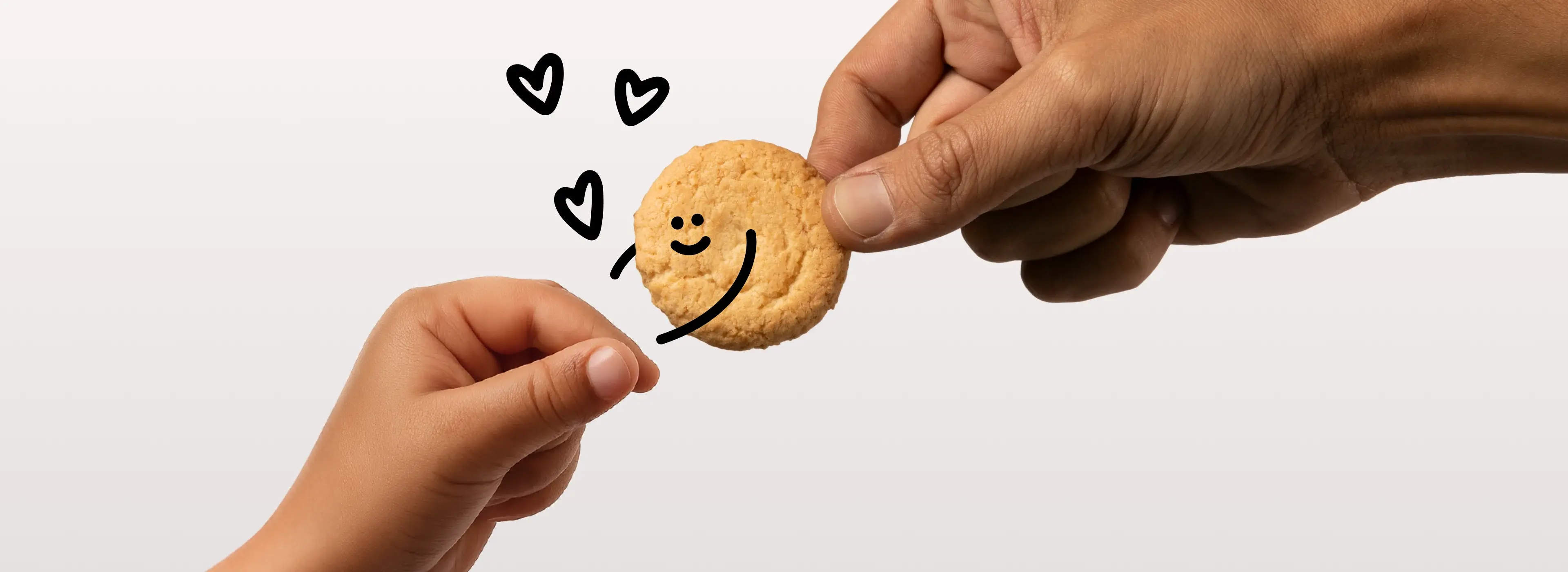 An adult hand passing a smiling cookie to a child's hand, with hearts drawn above